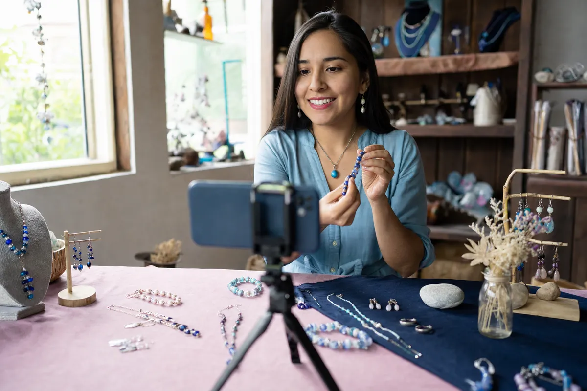 Joyera artesanal graba un video corto de sus piezas con un celular sobre un trípode
